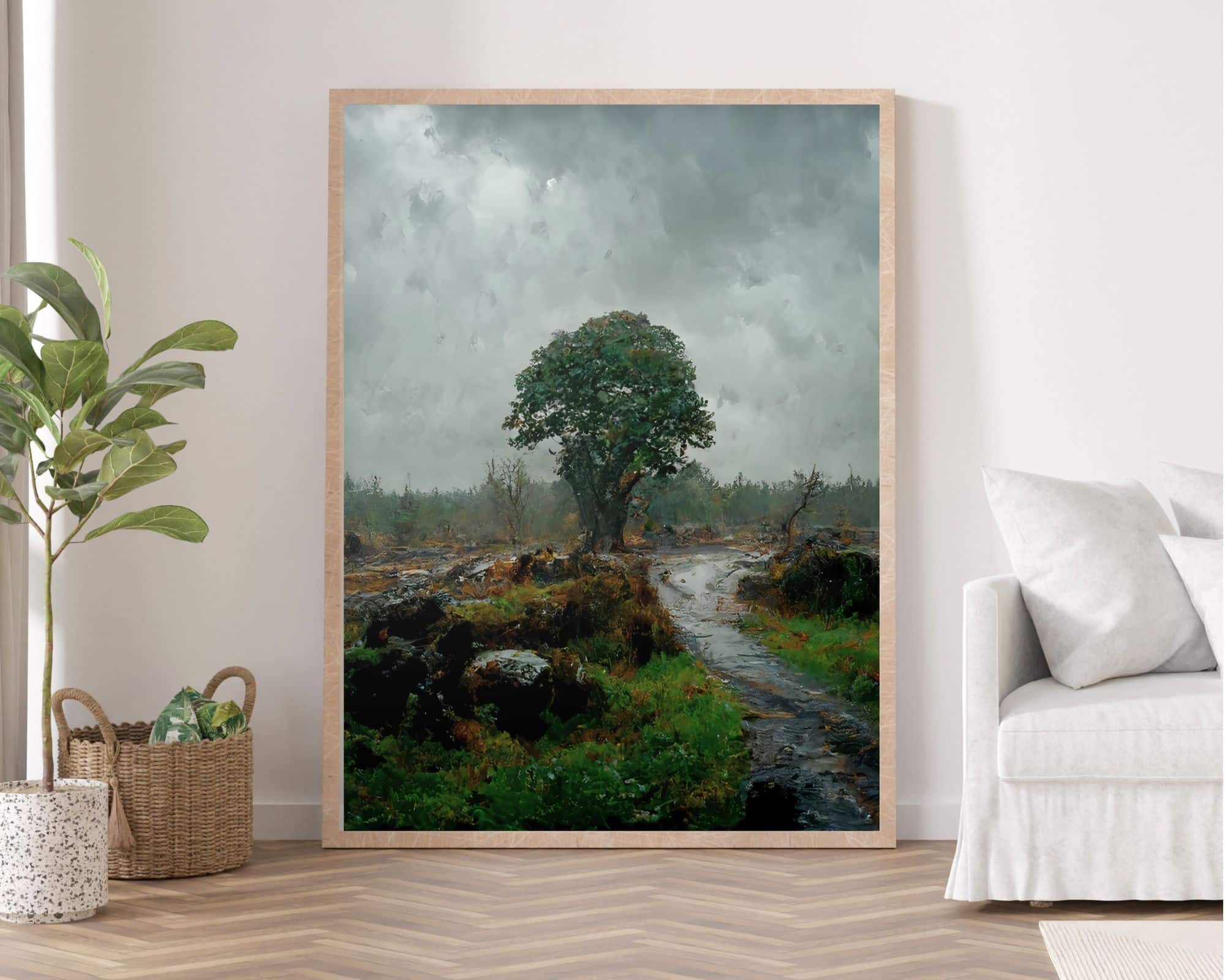 2129mo0 תמונה לחדר שינה סגנון ציור וינטג נוף טבע יער גשום עומדת על קיר. הציור, הממוקם במסגרת עץ, מתאר סצנה גדולה של עץ בודד על שביל עשב תחת שמים מעוננים, והוא ממוקם בחדר מינימליסטי עם ספה בז', עציץ וסלסלה ארוגה.