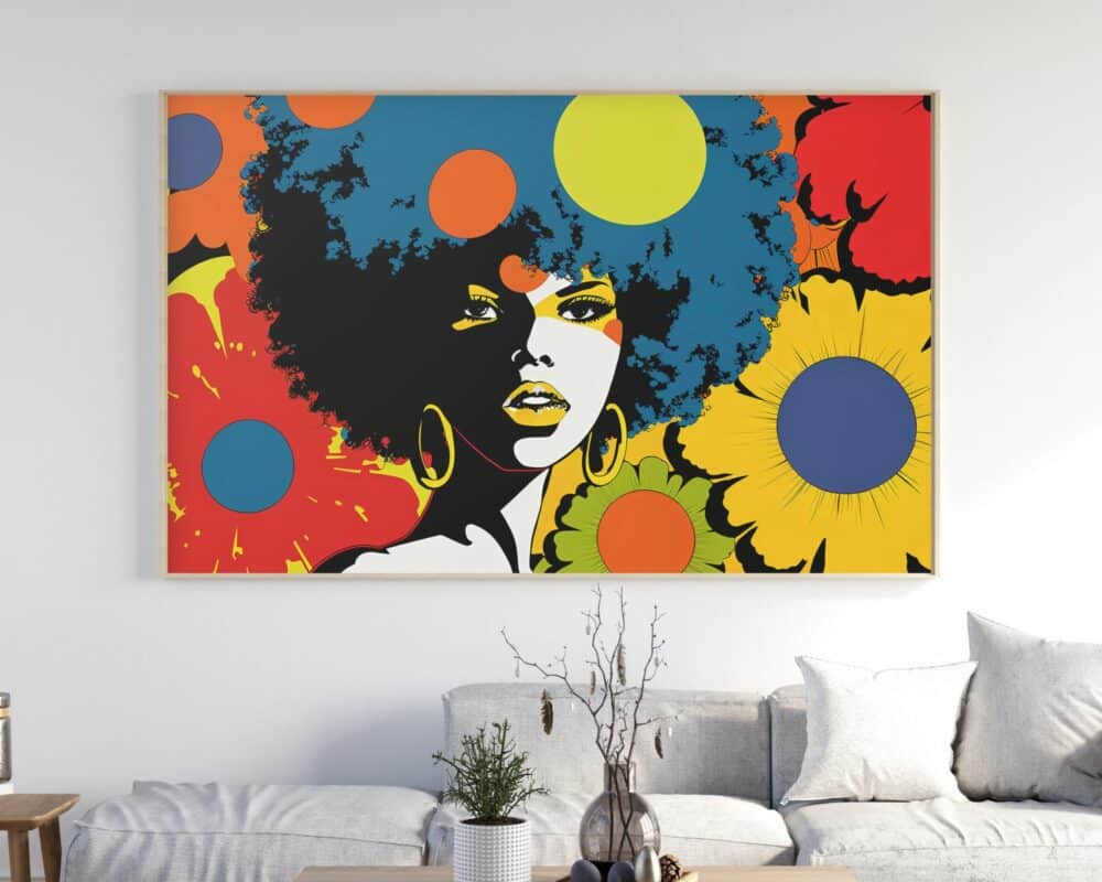 "תמונה מעל הספה נוסח רטרו אישה עם אפרו ופרחים צבעוניים" תלויה על קיר לבן מעל ספה אפורה בהירה. היצירה מציגה אישה עם תסרוקת אפרו מוקפת פרחים גדולים ותוססים באדום, צהוב וכתום. הספה מעוטרת בכריות לבנות ואפורות, משלימות עציץ קטן על שולחן הקפה.