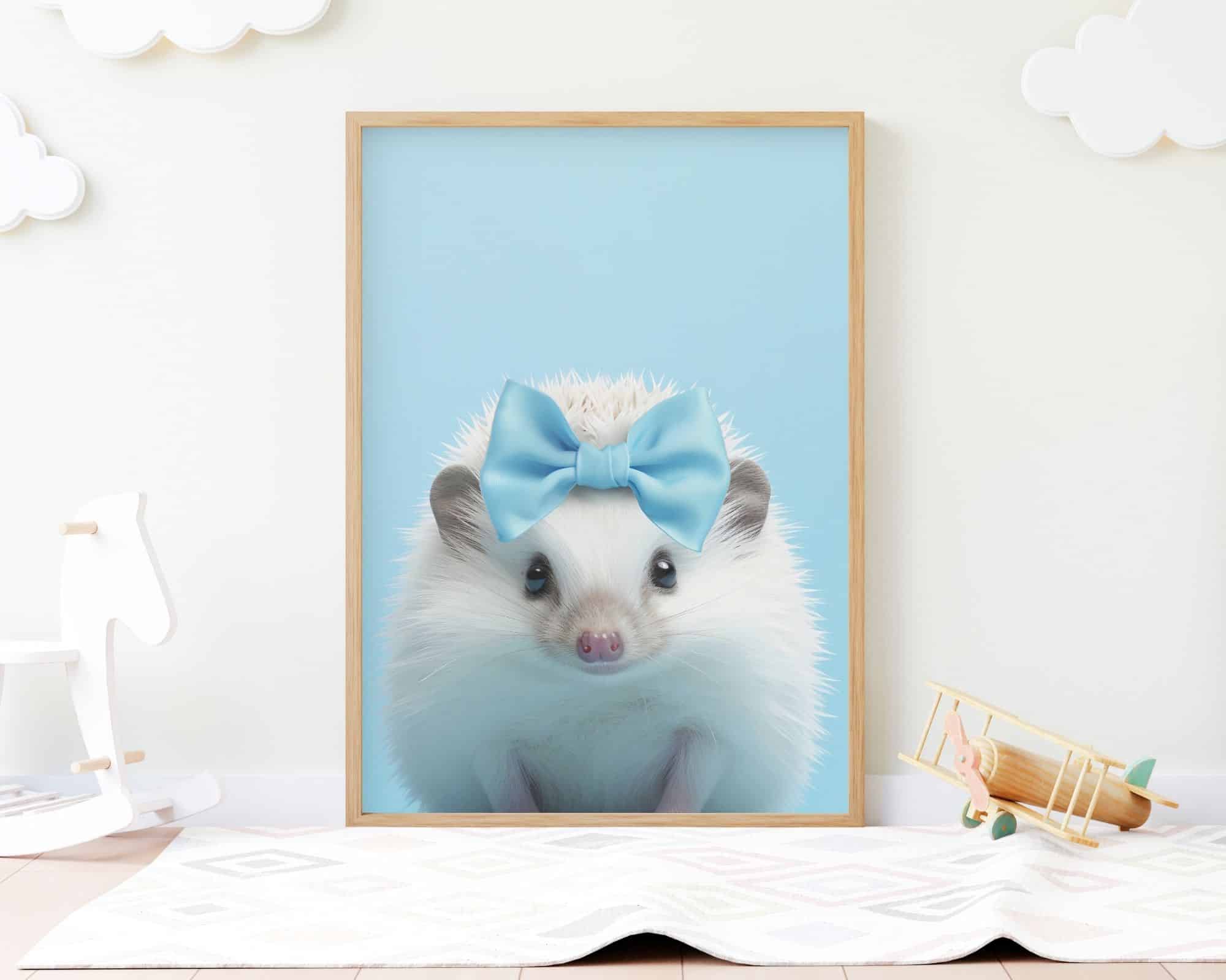 2383mo1 תמונה ממוסגרת שכותרתה "קיפוד בייבי עם פפיון על רקע תכלת" מציגה קיפוד עונד קשת כחולה, על רקע כחול פסטל. התמונה נשענת על קיר, מעוטרת במדבקות עננים רכות מעליו, לצד סוס נדנדה לבן ומטוס צעצוע. ההגדרה מציעה שזה בחדר של ילד.