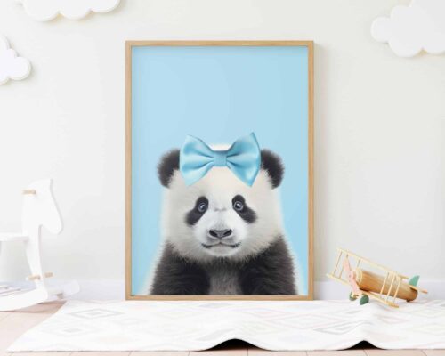 איור ממוסגר שכותרתו "פנדה בייבי עם פפיון על רקע תכלת" מציג דוב פנדה מקסים עם קשת כחולה על ראשו, על רקע כחול פסטל. המסגרת מוצגת עומדת על הרצפה בחדר ילדים בצבע בהיר, מוקפת ברהיטים וצעצועים לבנים, כולל סוס נדנדה מעץ ומטוס.