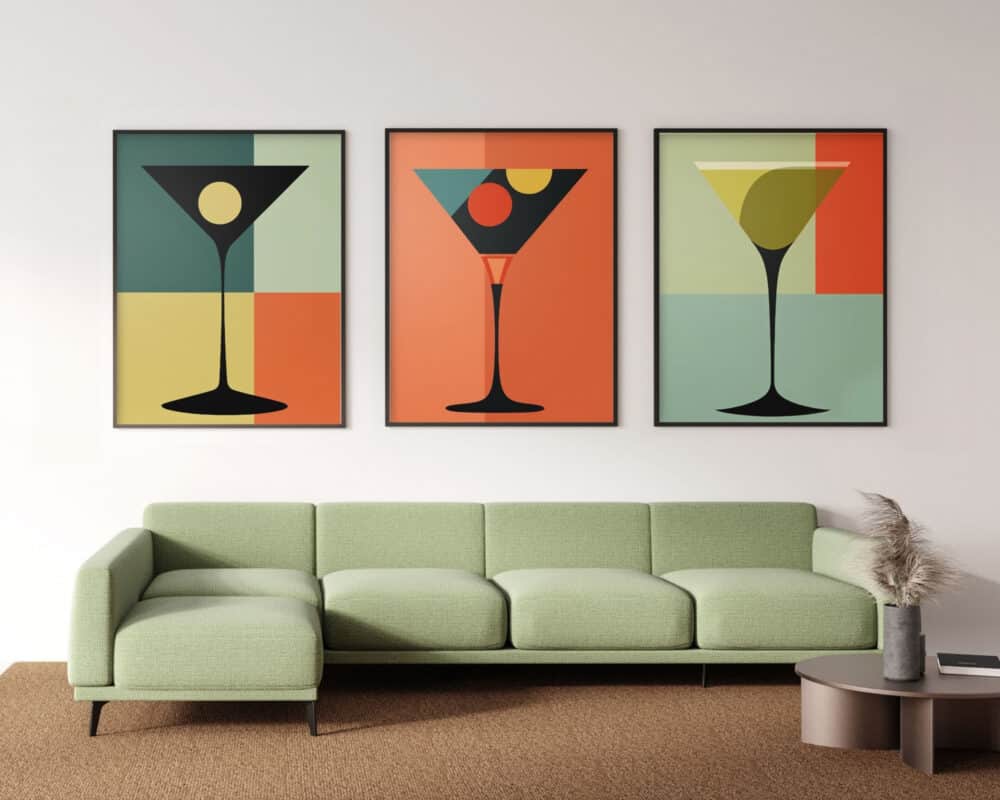 סלון מודרני כולל ספה ירוקה בהירה על רקע קיר לבן ומעליו ממוסגרת שילשיית פוסטרים לסלון מעל הספה סגנון מודרני מיד סנצ'ורי כוסות קוקטייל. כל יצירת אמנות מתארת כוס קוקטייל צבעונית ומסוגננת שונה. שולחן קפה עגול עם אגרטל זכוכית המכיל דשא פמפס יושב בקרבת מקום.