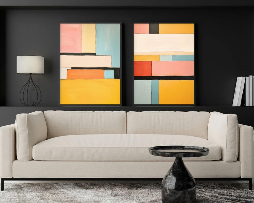 סלון מסוגנן כולל ספה בצבע בז' על קיר אפור כהה. שני חלקים מקולקציית "סט 2 תמונות לסלון נוסח אבסטרקט ריבועים צבעוניים" תלויים מעל הספה. מנורת שולחן מודרנית עם בסיס תיל נמצאת בצד שמאל, וכמה ספרים ממוקמים בצד ימין. שולחן קפה משיש שחור עגול בחזית.