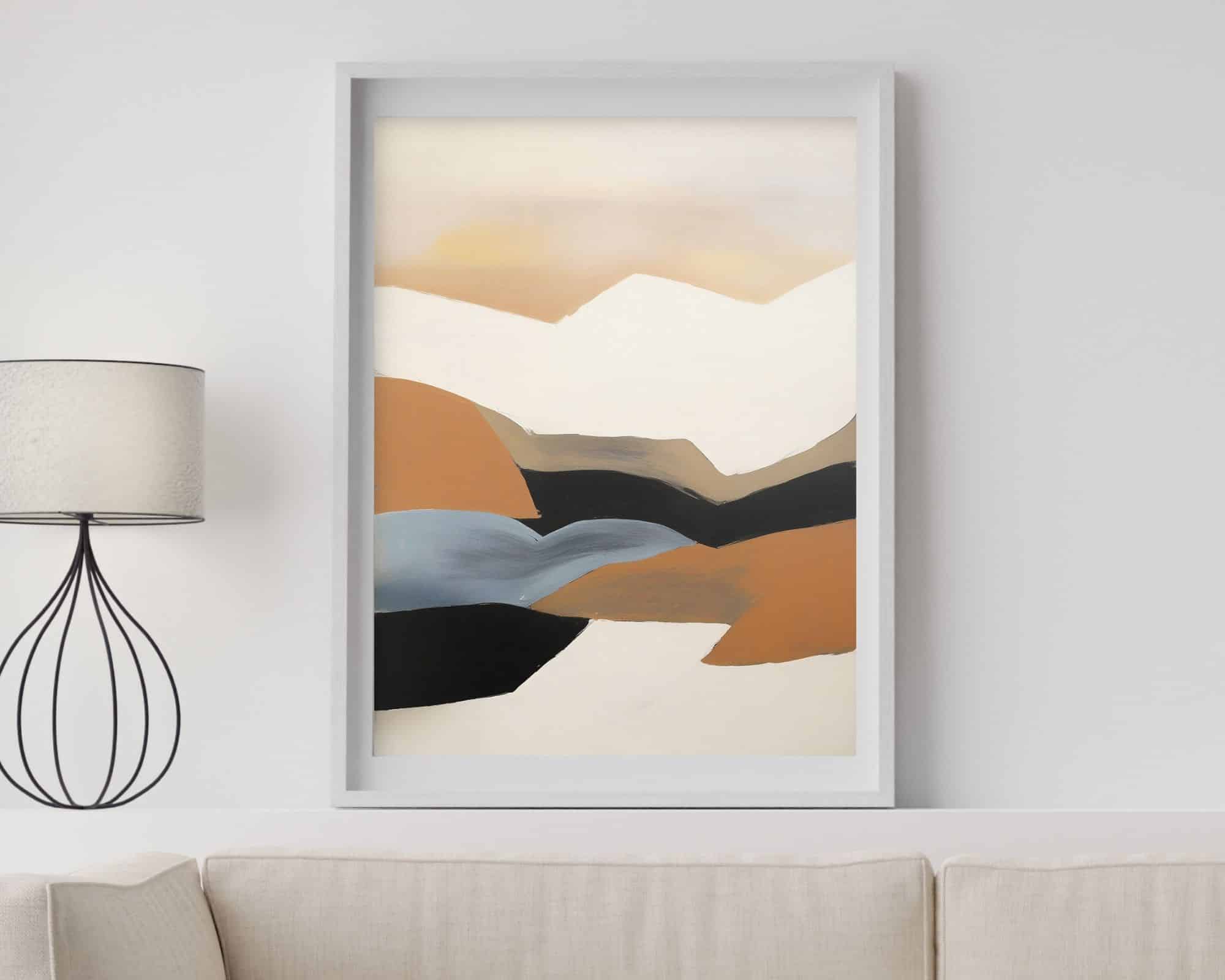 2456mo1 ציור מופשט ממוסגר שכותרתו "תמונה למשרד נוסח אבסטרקט נוף הרים בגווני אדמה" תלוי על קיר לבן מעל ספה בהירה. יצירות האמנות מציגות צורות רכות וזורמות בגווני בז', חום, שחור וכחול, הדומים לנוף שליו. מנורה מודרנית עם בסיס תיל עומדת משמאל.