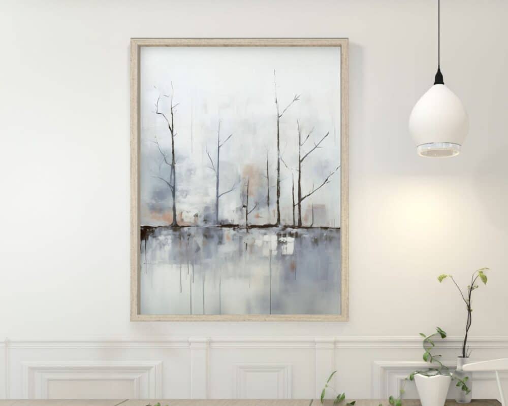 ציור מינימליסטי שכותרתו "תמונה לפינת אוכל נוסח אבסטרקט יער בחורף בגווני כחול" של עצים עקרים המשתקפים במים תלוי על קיר לבן. הגרפיקה כוללת גוונים עמומים של אפור, לבן וחום. מנורת תליון מודרנית ולבנה מוארת בקרבת מקום, ועציץ ירוק מוסיף נופך של טבע לסצנה.