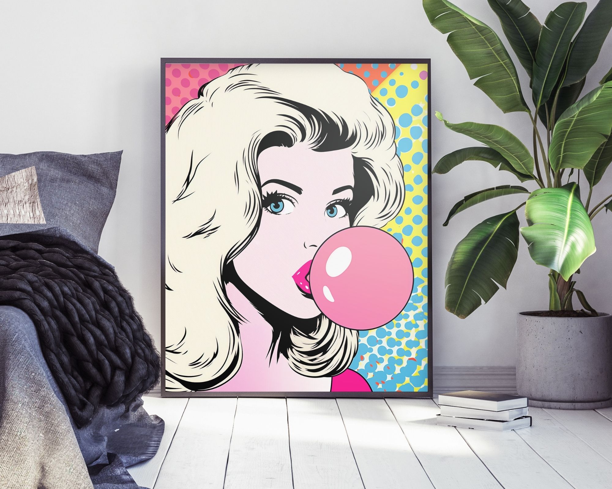 2485mo1 התמונה לחדר נוער נוסח פופ ארט בלונית עם בלון מסטיק מציגה איור פופ ארט תוסס ממוסגר של אישה בלונדינית נושבת בועת מסטיק ורודה גדולה, על קיר לבן. היצירה מתהדרת ברקע תוסס ומנוקד בגווני כחול, צהוב וורוד. בקרבת מקום ניתן לראות צמח ירוק וחלק ממצע עם מצעים כהים.
