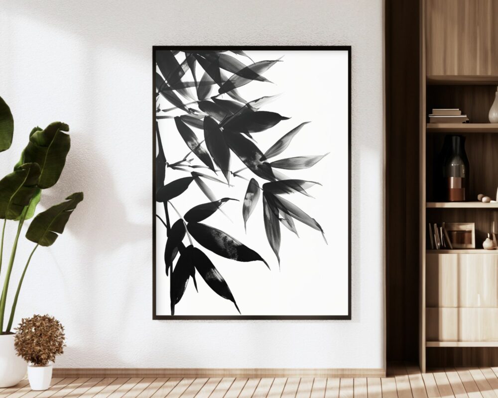 פנים מודרני הכולל פריט גדול ממוסגר, תמונה למשרד עיצוב מינימליסטי צללית עלי במבוק בשחור לבן, על קיר לבן. משמאל עציץ בעל עלים רחבים. מימין, מדף עץ מכיל פריטי נוי שונים. רצפת העץ מוסיפה חמימות לחלל.