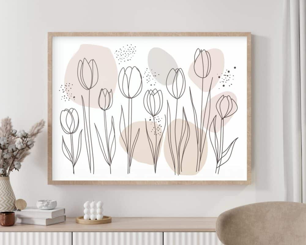 התמונה מעל המיטה בעיצוב מינימליסטי פרחים בקווי מתאר מציגה פרחי צבעונים פשוטים עם קווי מתאר על רקע צורות פסטל מופשטות. פריט אמנות קיר ממוסגר מינימליסטי זה מוצג באלגנטיות מעל מזנון לבן, המעוטר בחפצי קרמיקה ואגרטל של פרחים מיובשים.