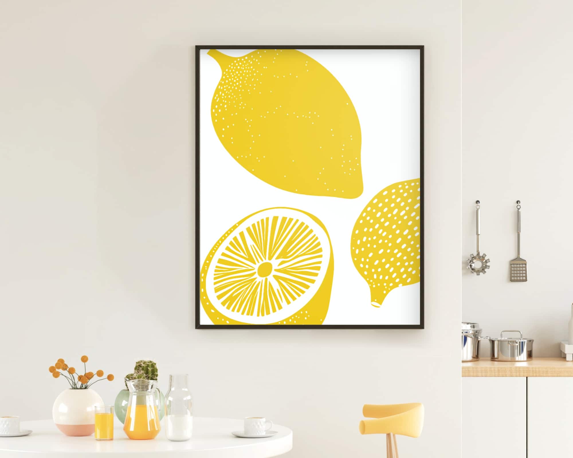 2600mo1 מטבח מודרני כולל משטח לבן עם אגרטל פרחים ובקבוקי זכוכית שונים. מעל הדלפק תלויה "תמונה למטבח בעיצוב מינימליסטי לימונים צהובים", הדפס ממוסגר מינימליסטי של שני לימונים, אחד שלם ואחד פרוס לשניים, בגווני צהוב עזים. כלי מטבח תלויים יפה על הקיר.