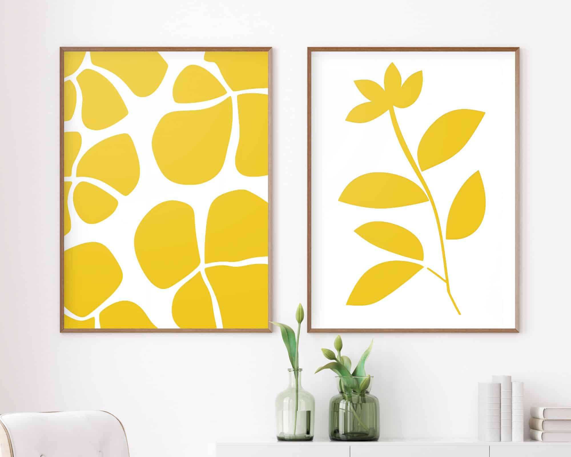 2601mo1 שני יצירות אמנות אבסטרקטיות ממוסגרות מתוך סט סט פוסטרים לסלון נוסח סט מינימליסטי פרחים צהובים מעטרים קיר לבן. היצירה השמאלית מציגה צורות צהובות, לא סדירות על רקע לבן, בעוד היצירה הימנית מציגה צללית בוטנית צהובה פשוטה. מתחת, ארון לבן מכיל שני אגרטלי זכוכית ירוקים עם צמחים.