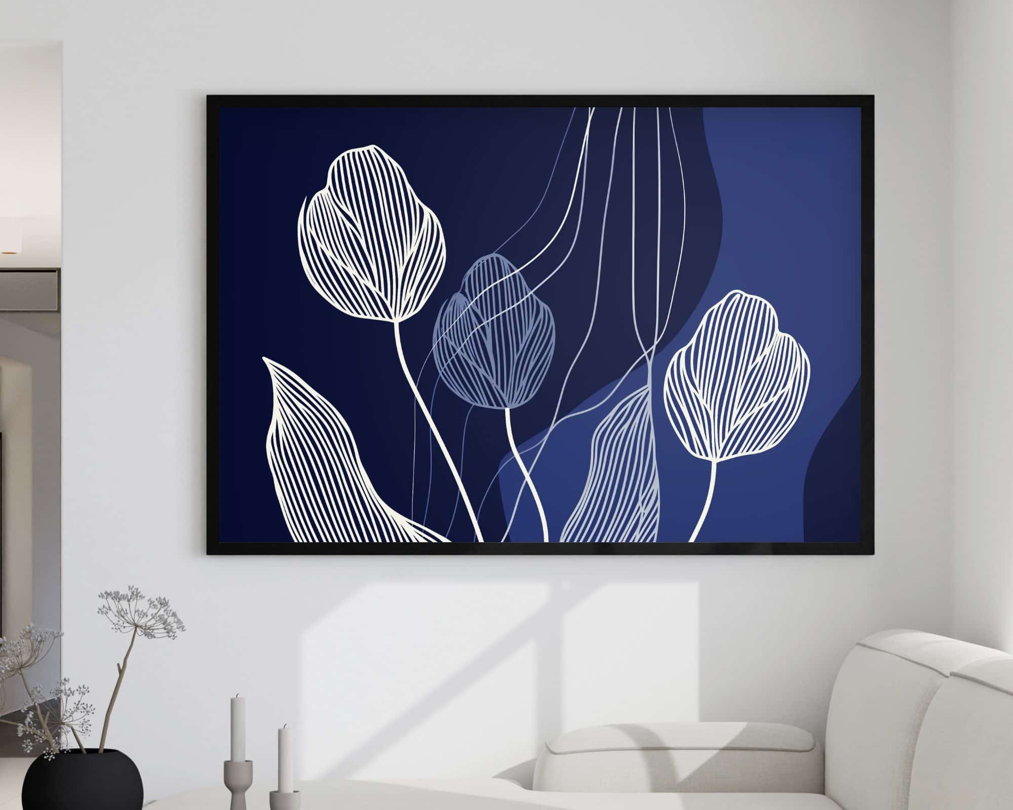 2602mo1 יצירה ממוסגרת - שכותרתה "תמונה מעל הספה בעיצוב מינימליסטי פרחים על רקע כחול כהה" - תלויה על קיר לבן מעל ספה בז'. היצירה מתהדרת בעיצובי פרחים לבנים ומינימליסטיים על רקע כחול כהה עם קווים זורמים. בסמוך, אגרטל קטן עם ענפים יבשים ושני נרות לא דולקים מוסיפים לעיצוב.