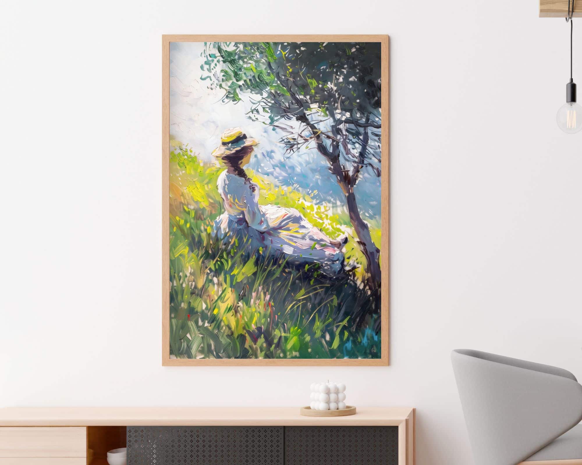 2620mo1 ציור ממוסגר שכותרתו "תמונה לפינת אוכל ציור וינטג' אישה מתחת לעץ", המתאר אדם בשמלה לבנה וכובע קש יושב מתחת לעץ באחו שטוף שמש, תלוי על קיר לבן. אמנות הקיר היא מעל מזנון מודרני עם פריטי נוי, וחלק מכיסא מינימליסטי נראה בצד ימין.