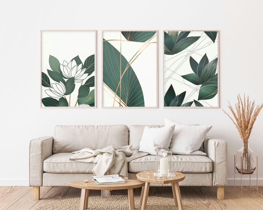 סלון נעים כולל ספה בצבע בז' עם כריות לבנות ובז'. מעל הספה שלושה הדפסים ממוסגרים מקולקציית סט 3 תמונות לסלון "וקווי מינימליסטי עלים" המציגים עלים ירוקים ועיצובים מופשטים. שולחן קפה קטן מעץ מציג נר וספרים, בעוד סידור דשא יבש מדגיש את הפינה.