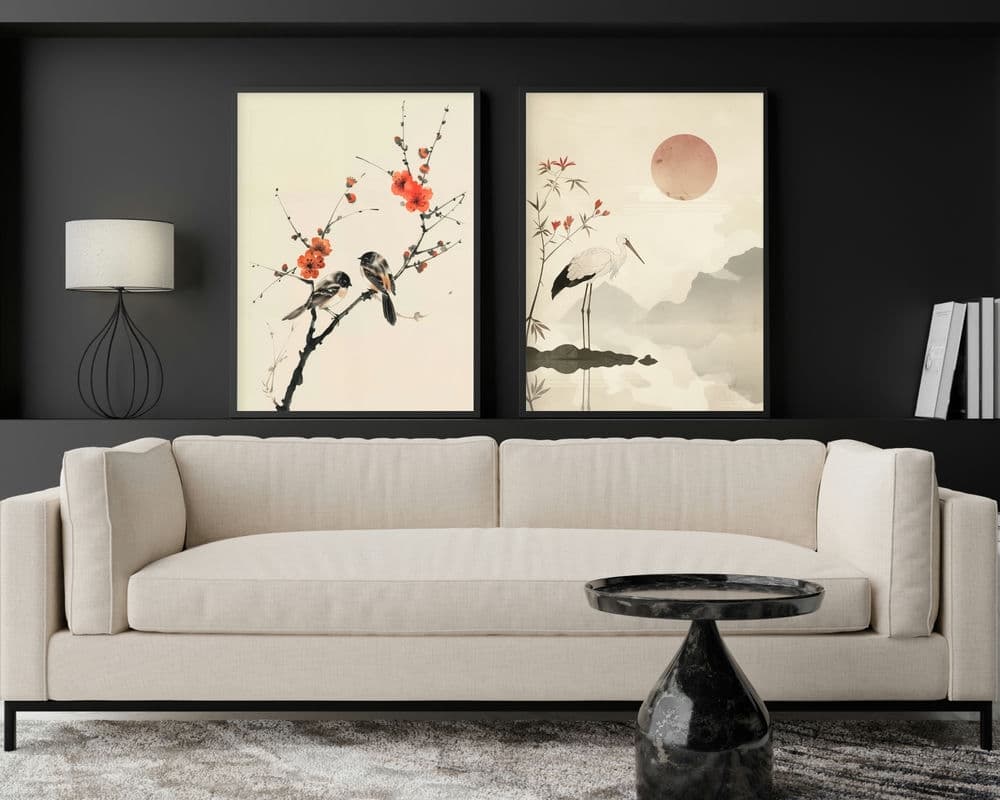 סלון מודרני עם ספה בצבע בז' בהיר, שולחן קפה משיש שחור וקיר שחור. שני יצירות אמנות ממוסגרות מקולקציית "סט 2 תמונות לסלון נוסח וינטג' יפני ציפורים ועגור" תלויות מעל הספה: האחת מתארת ציפורים על ענף פורח, והשנייה מציגה עגורים ליד בריכה עם שמש אדומה. מנורה אלגנטית וספרים נמצאים בצדדים.