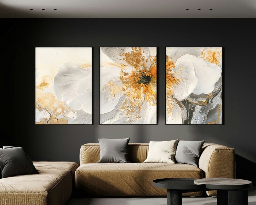 סלון מודרני עם ספת חתך בז' וכמה כריות אפור ולבן. הקיר מאחורי הספה כהה, מודגש על ידי סט 3 תמונות לסלון פרח זהב ולבן נוסח מינימליסטי, יצירת אמנות טריפטית הכוללת עיצובי פרחים מופשטים בגווני לבן, זהב ואפור. שולחן קפה עגול ושחור נמצא בחזית.